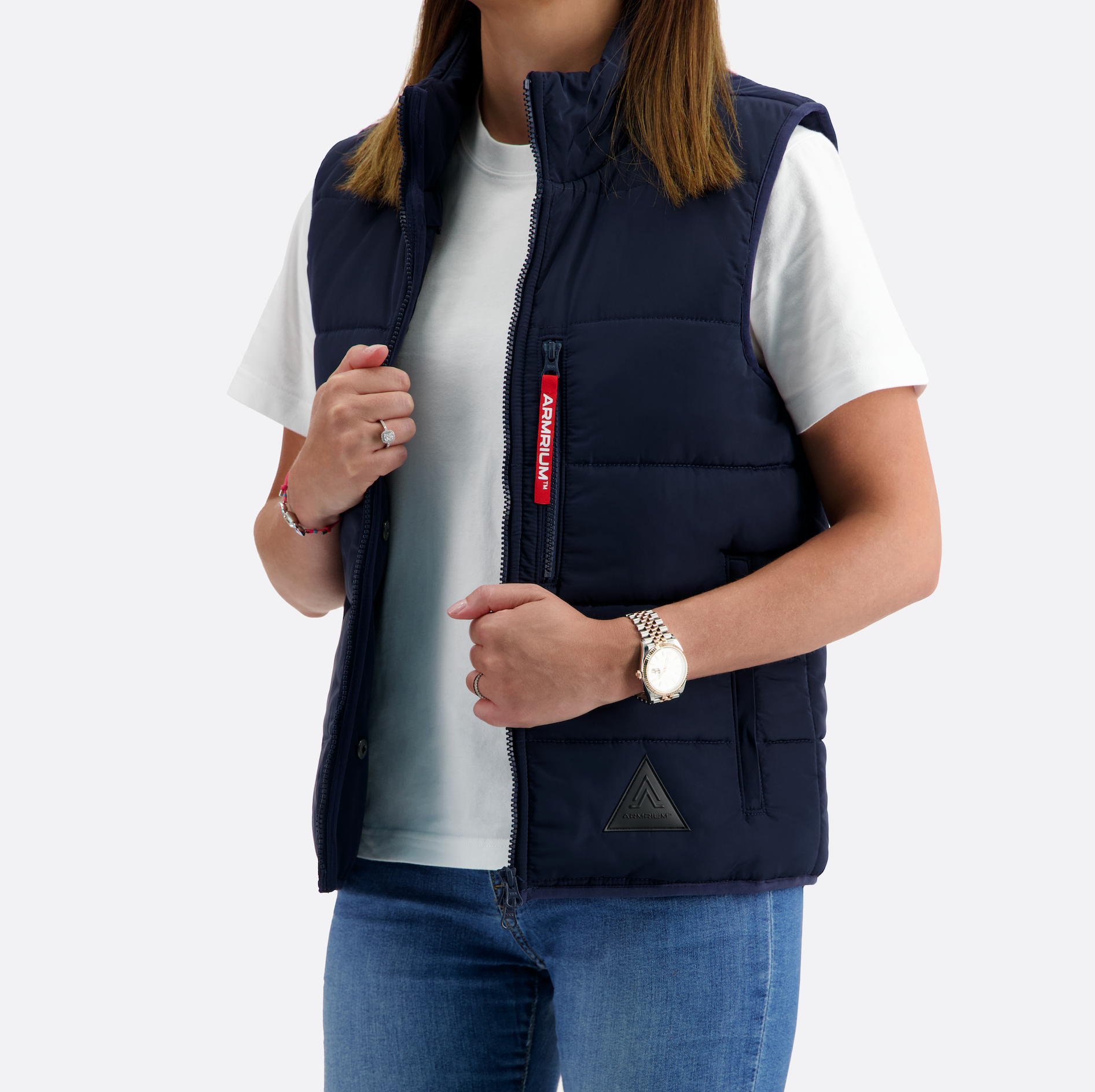 Person wearing a navy blue puffer vest with a red label on a white background